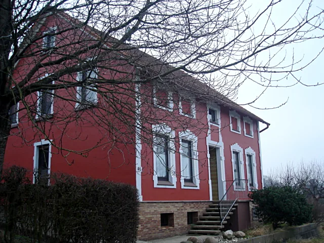 Rote Hausfassade mit weißen Fensterfaschen, Ansicht von der Seite